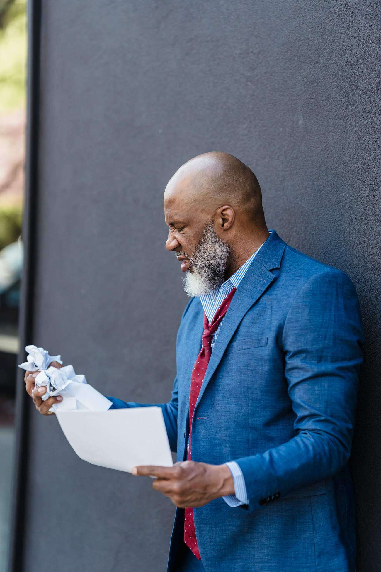 A professional man in a suit madly holds and crumples some papers