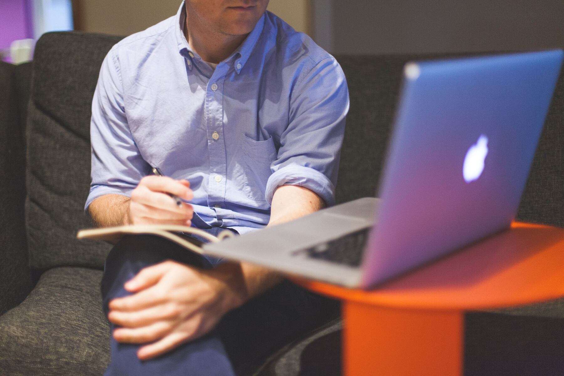 A man sitting on a couch with a laptop in front of him