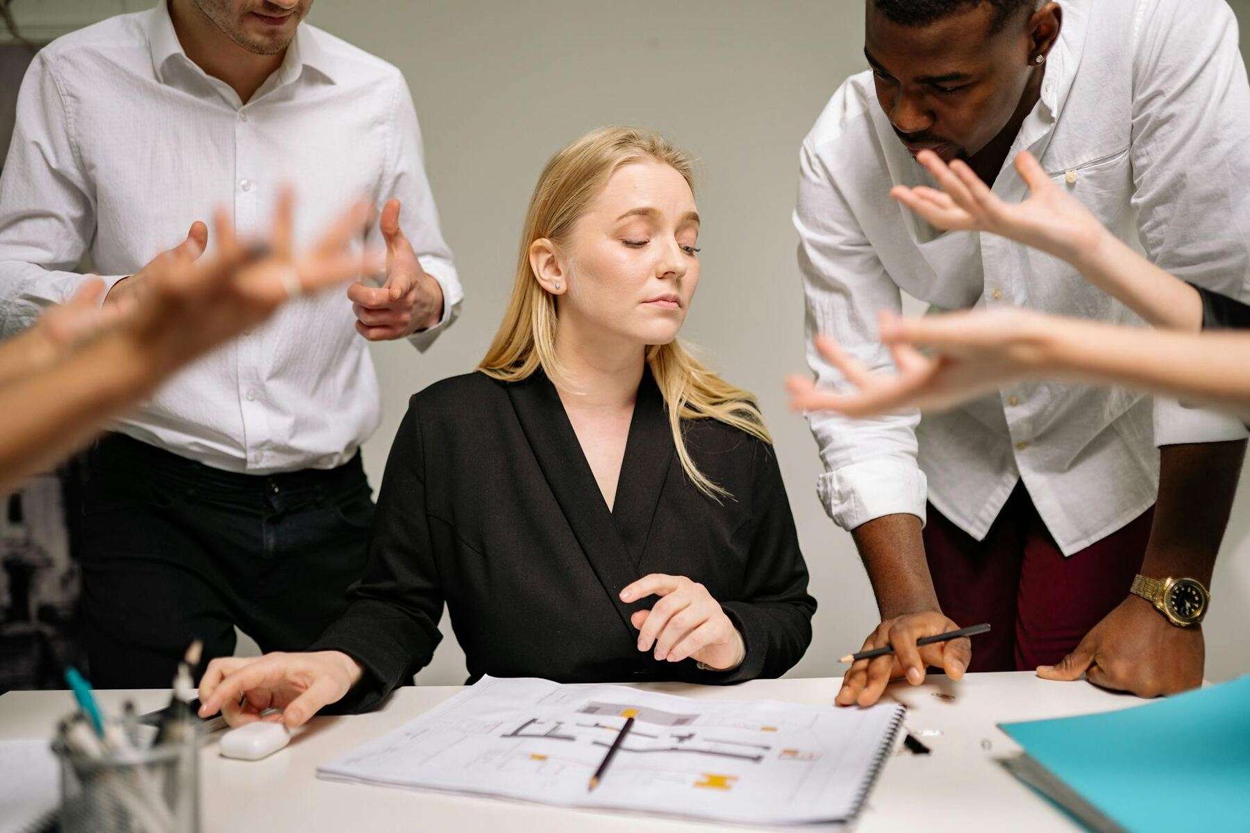 Woman overseeing documents while seated, while her coworkers are standing beside her
